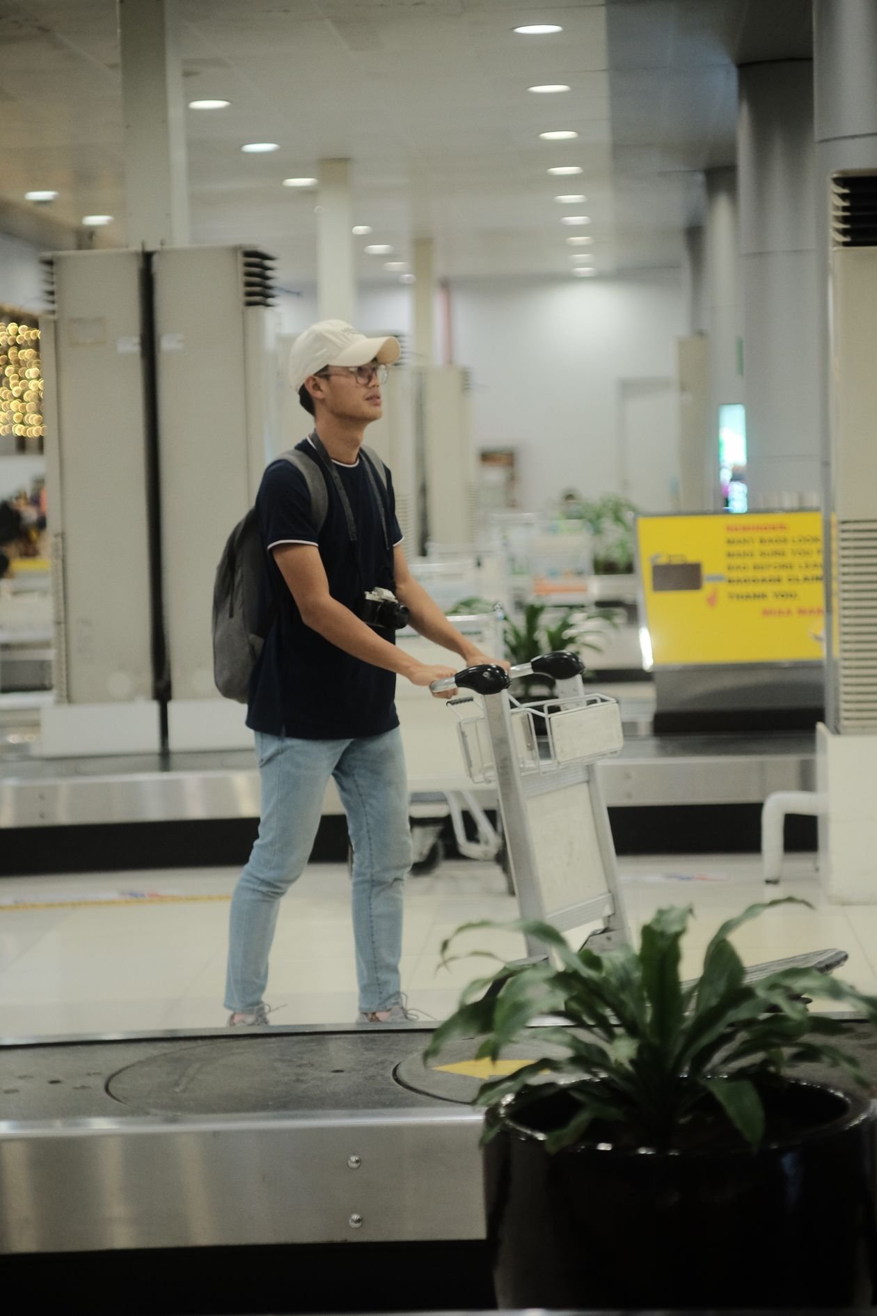 Student with a luggage trolley at airport baggage claim