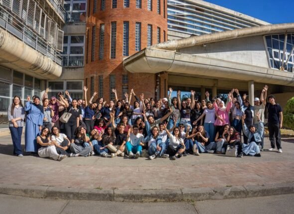 Large group of international students celebrating outside a modern university building